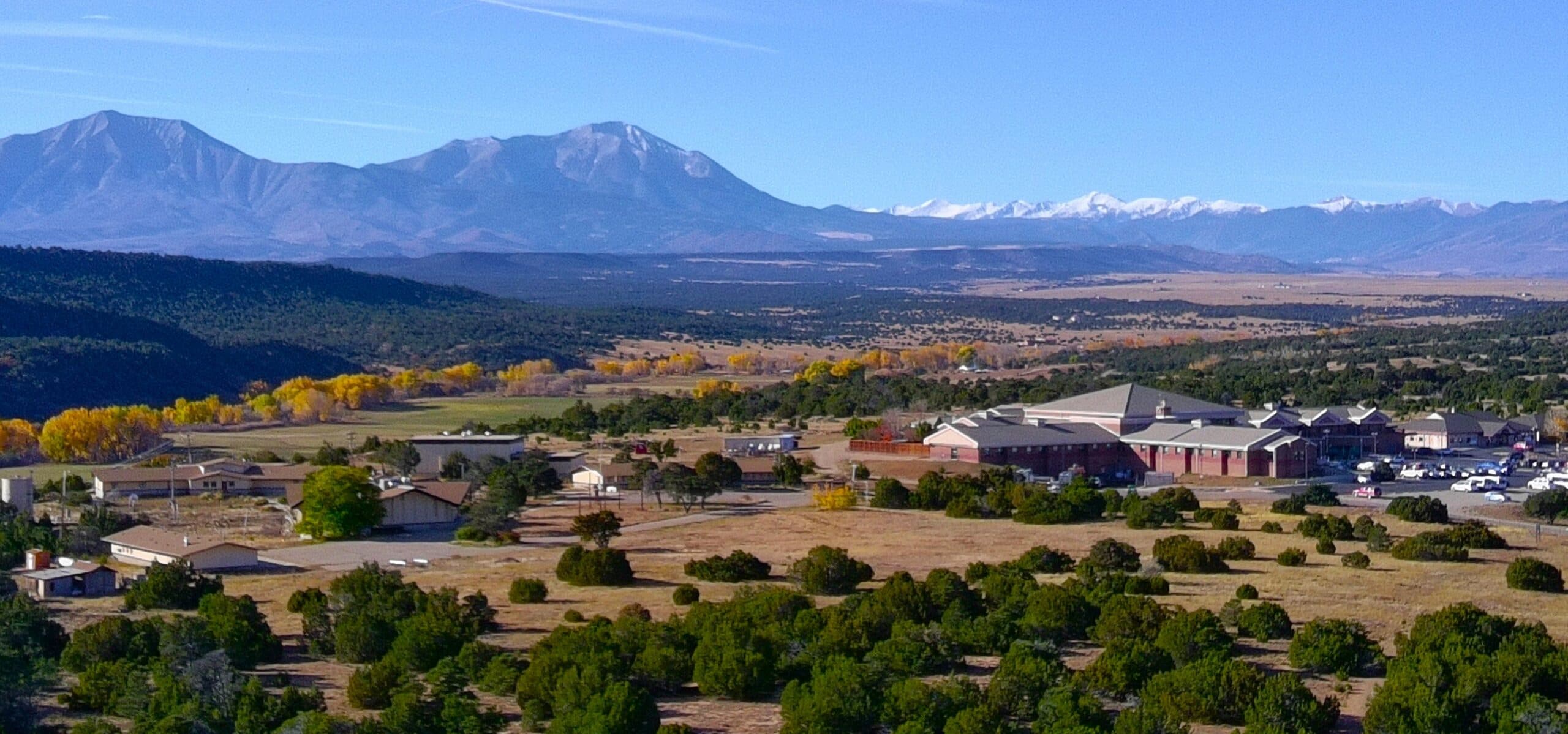 Aerial view of the Spanish Peaks Regional Health Center campus among juniper and autumn cottonwoods, with the Spanish Peaks behind.